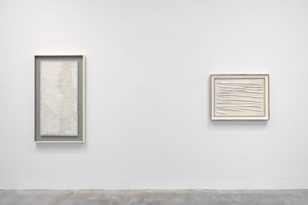 a white wall with white works of art on the wall