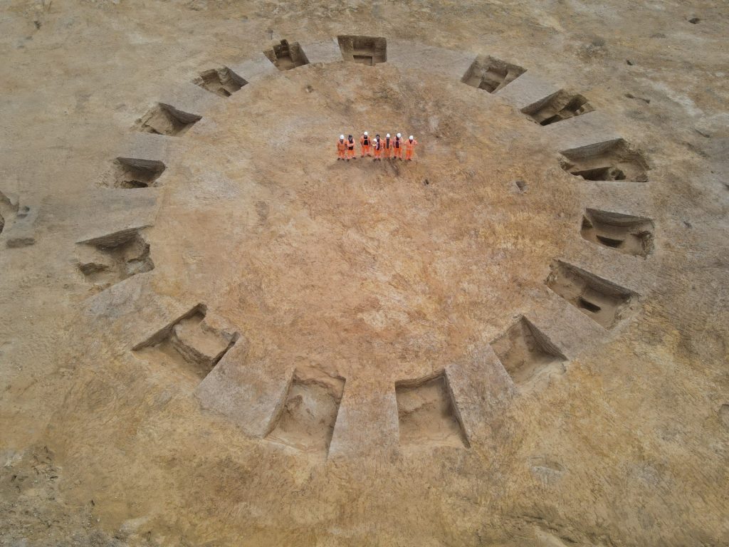 overhead view of people in orange standing in the center of holes