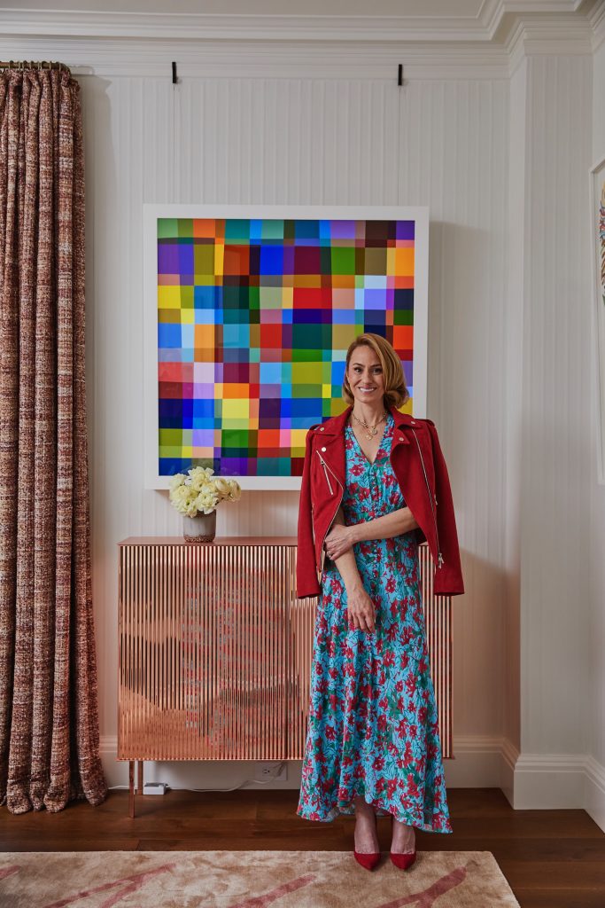 A woman poses for the camera with an abstract artwork behind her