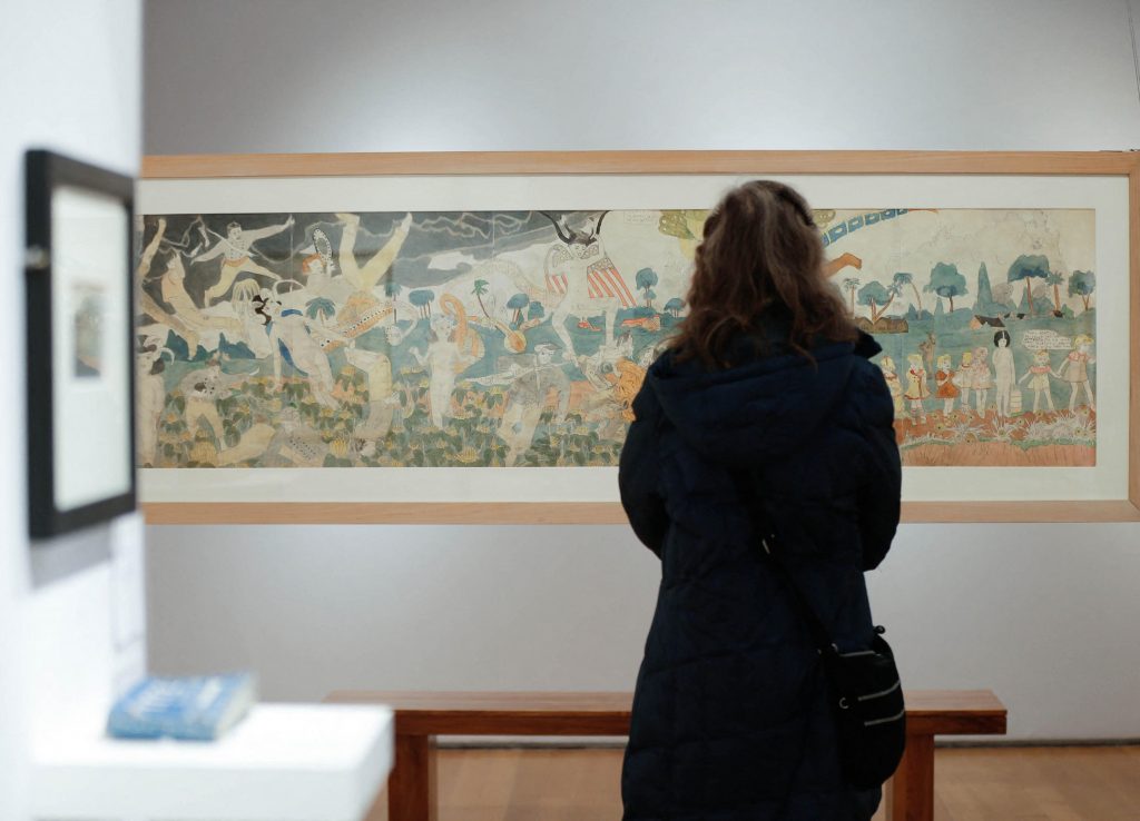 Visitor stands before long Henry Darger panorama drawing depicting fantastical battle scenes and children.