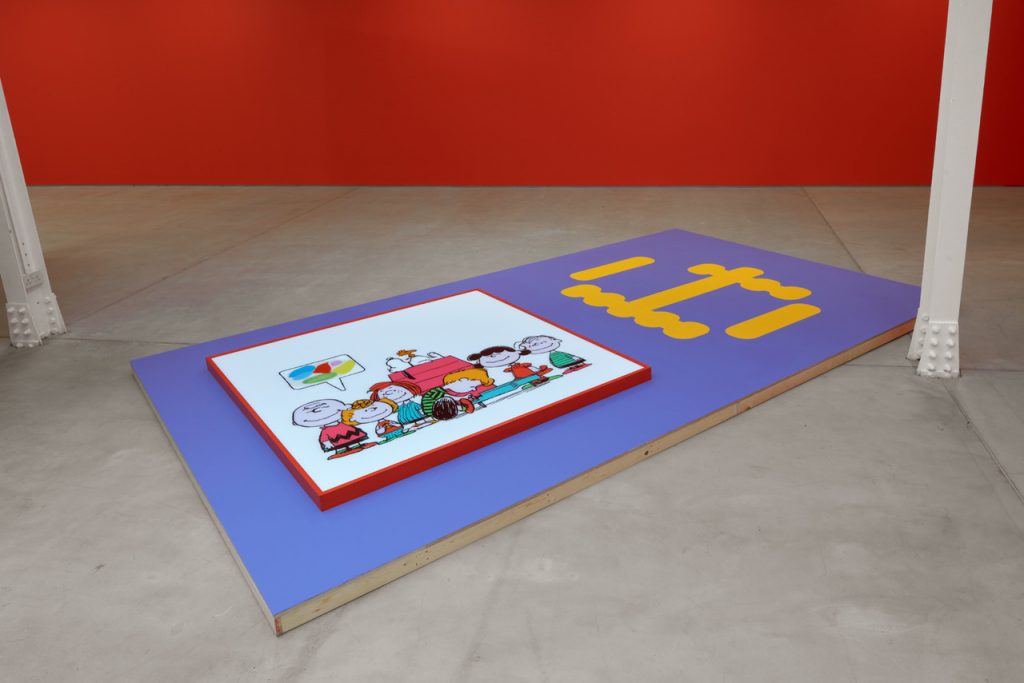 A painting in purple background on the floor, against a red wall.