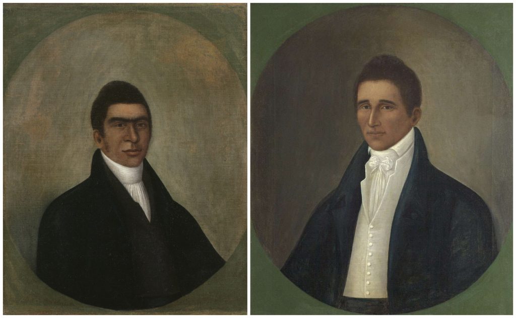 Two side-by-side oval-format portrait paintings by Joshua Jonson of men shown from the chest up against softly shaded green-gray backgrounds. On the left, a man with short dark hair and strong brows wears a black coat and high white collar, facing slightly to the right with a calm expression. On the right, another man with short dark hair wears a dark blue coat over a white shirt with a high collar and tied cravat, facing slightly to the left. Both portraits are rendered in a restrained early 19th-century style with minimal background detail.
