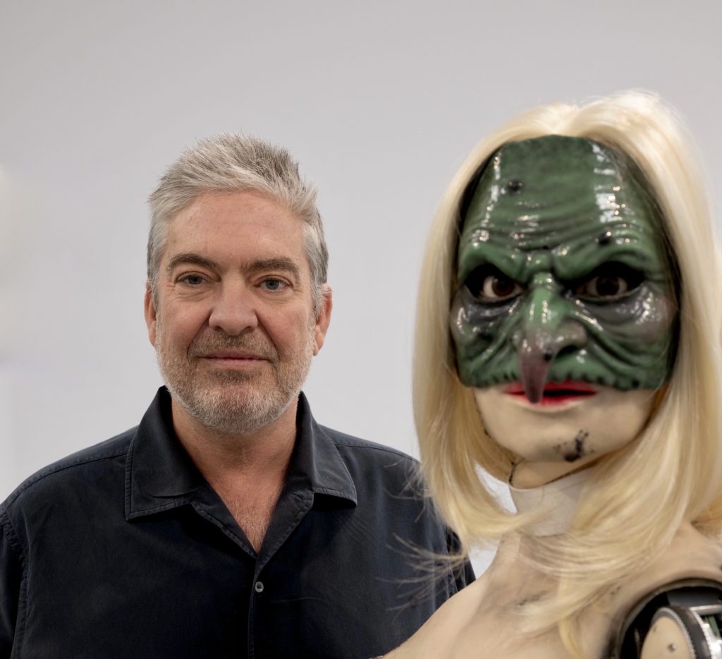 an image of the collector Laurent Asscher with a wicked looking mannequin with blond hair and a green mask over the eyes