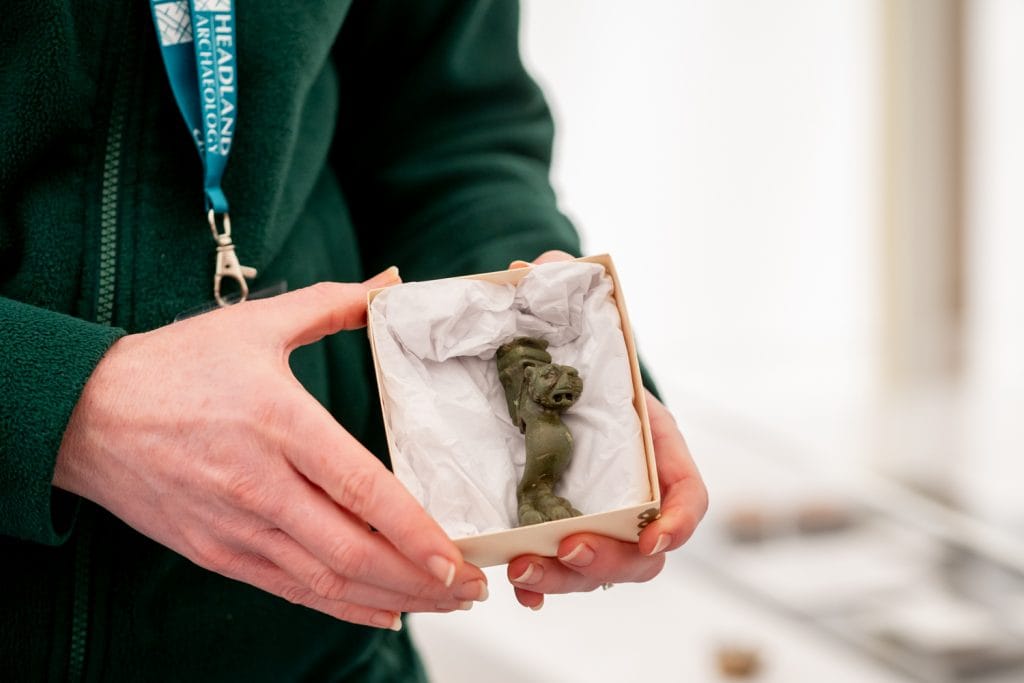 a hand holding a box with a small metal lion's foor