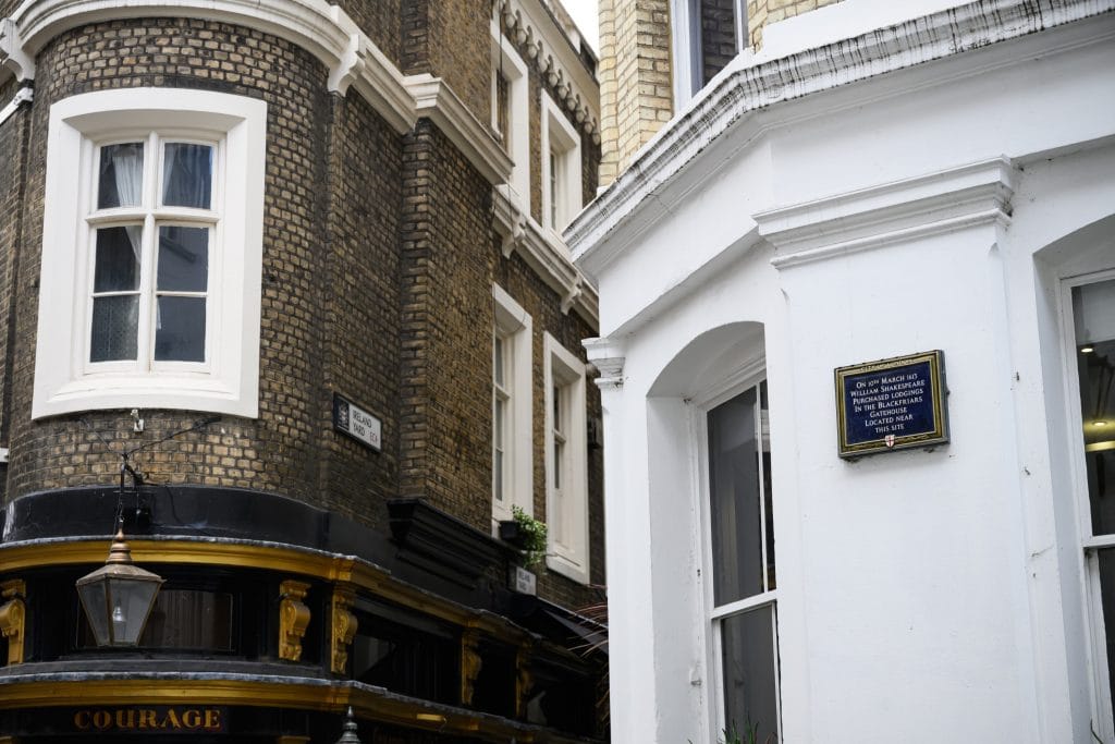 Historic London street corner with brick buildings, pub frontage, and plaque marking Shakespeare-related location