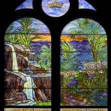 a stained glass window with a waterfall and plants