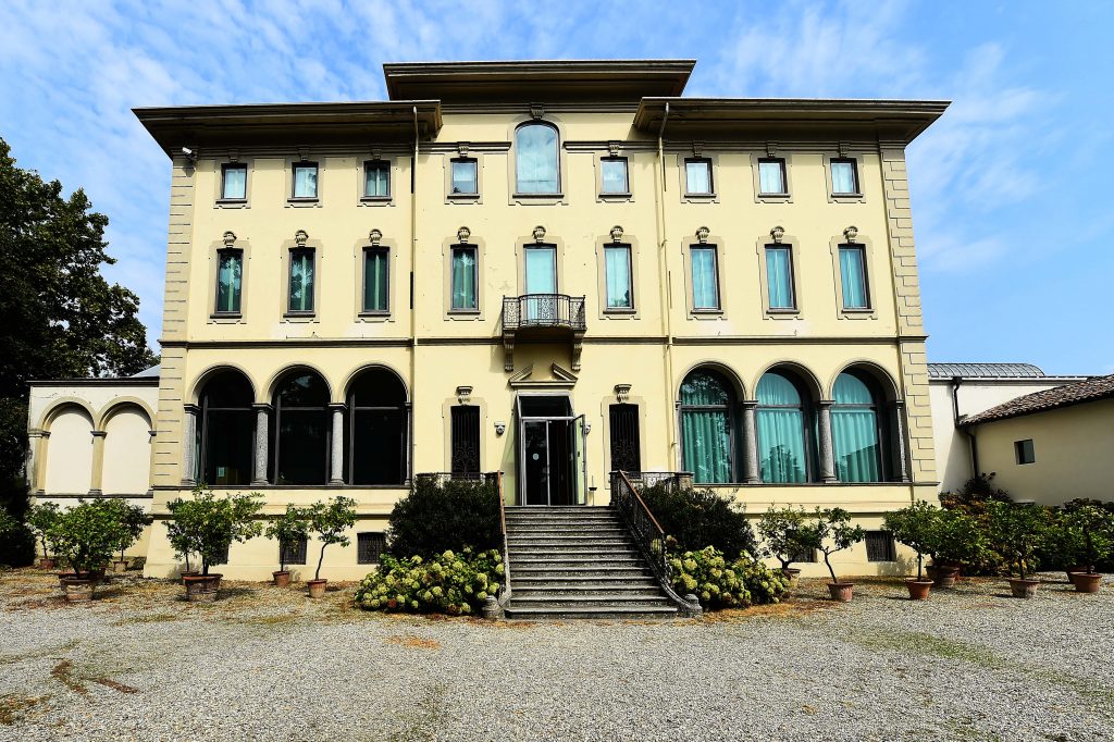 Symmetrical neoclassical villa housing the Magnani Rocca Foundation facade with arched windows, central balcony, and staircase leading through garden courtyard